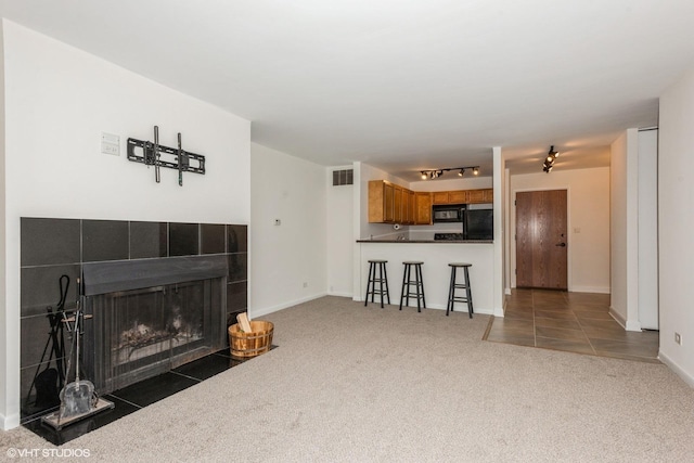 living room with dark carpet and a tiled fireplace