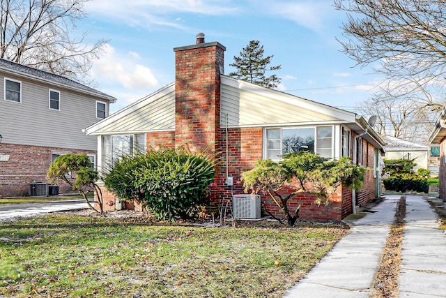 view of side of home featuring a lawn and central AC