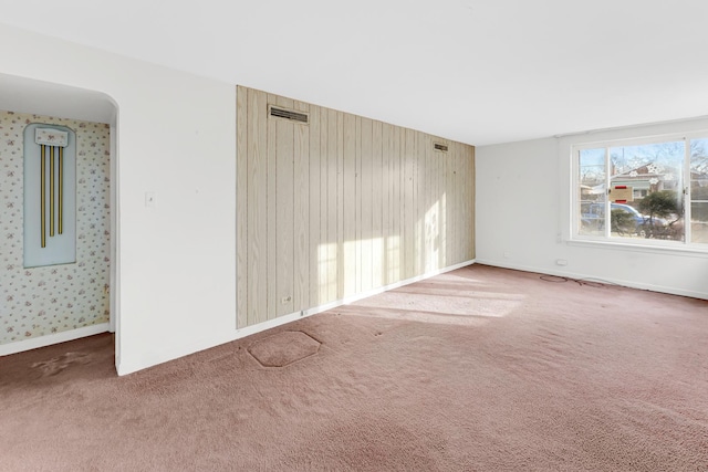 unfurnished room with carpet flooring and wooden walls