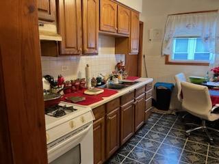 kitchen featuring tasteful backsplash, sink, white range with gas stovetop, and custom exhaust hood