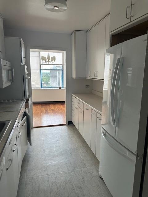 kitchen featuring a notable chandelier, white cabinetry, and white appliances