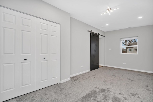 unfurnished bedroom with carpet, a barn door, and a closet