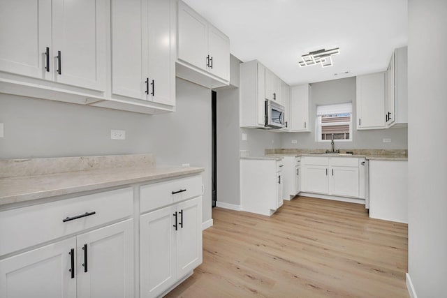 kitchen featuring white cabinets, light hardwood / wood-style floors, and sink