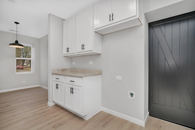 kitchen featuring white cabinets, light hardwood / wood-style floors, and hanging light fixtures