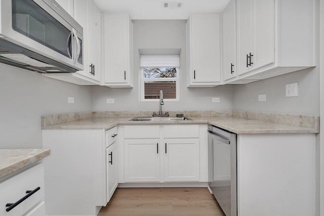 kitchen featuring white cabinetry, sink, light hardwood / wood-style flooring, and appliances with stainless steel finishes