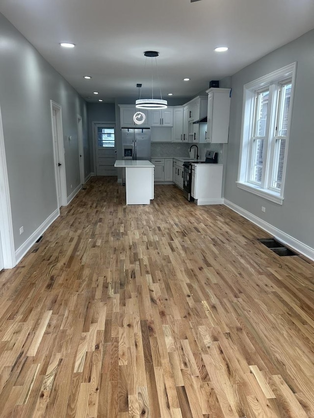 kitchen featuring open floor plan, stainless steel refrigerator with ice dispenser, a wealth of natural light, and range with electric stovetop