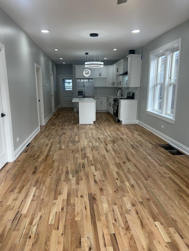 kitchen with visible vents, light wood-style flooring, stainless steel refrigerator with ice dispenser, a kitchen island, and electric range oven