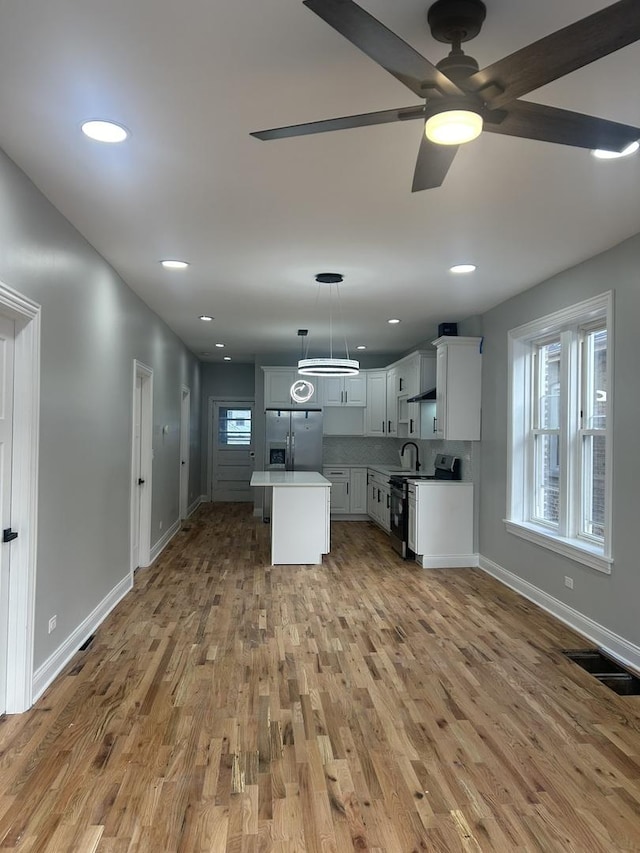 kitchen featuring baseboards, visible vents, light wood finished floors, stainless steel refrigerator with ice dispenser, and white range with electric stovetop