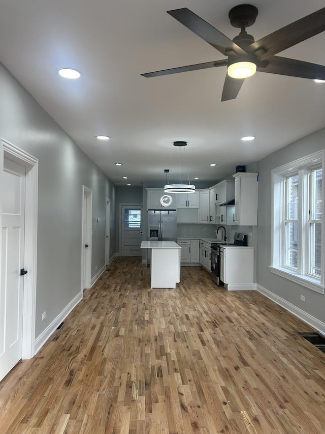 kitchen featuring a wealth of natural light, stainless steel fridge, light wood-type flooring, and a sink