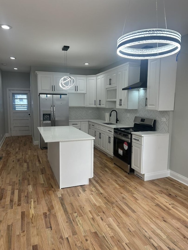 kitchen featuring a sink, stainless steel appliances, wall chimney exhaust hood, light wood finished floors, and light countertops