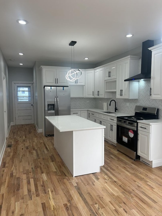 kitchen with light countertops, wall chimney exhaust hood, appliances with stainless steel finishes, and a sink