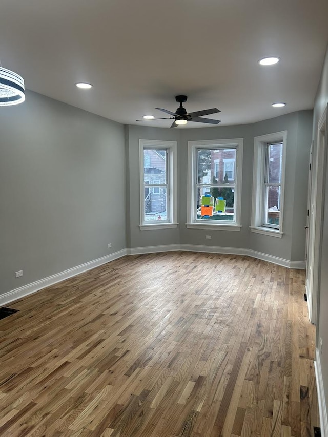 spare room featuring baseboards, a healthy amount of sunlight, and wood finished floors