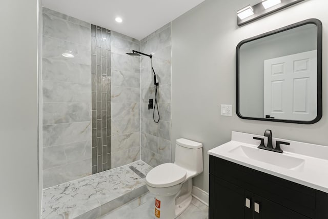 bathroom featuring tiled shower, toilet, vanity, and baseboards