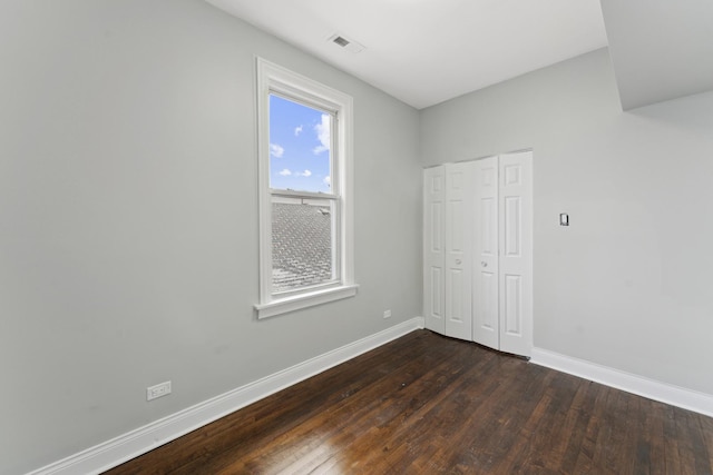 unfurnished bedroom with visible vents, baseboards, dark wood-type flooring, and a closet