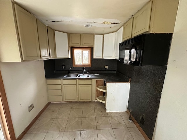 kitchen with cream cabinets, light tile patterned floors, and sink