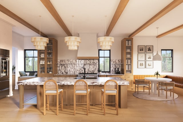 kitchen featuring a breakfast bar area, light stone counters, a wealth of natural light, custom range hood, and decorative light fixtures