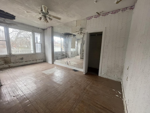 unfurnished room featuring hardwood / wood-style floors, a textured ceiling, a baseboard radiator, and ceiling fan