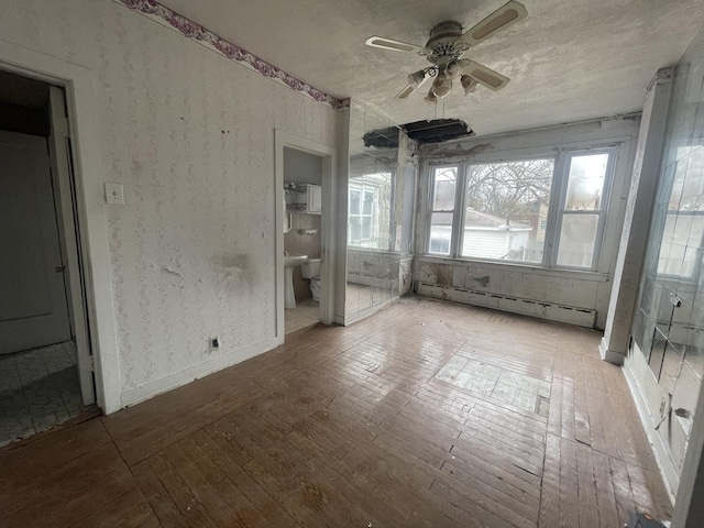 unfurnished sunroom featuring ceiling fan and a baseboard radiator