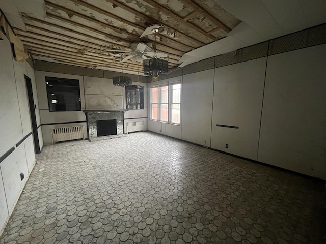 basement with a high end fireplace, radiator heating unit, and ceiling fan