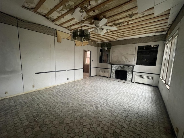 unfurnished living room featuring a fireplace, ceiling fan, radiator heating unit, and a towering ceiling