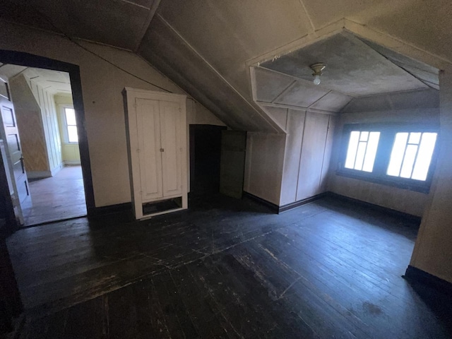 additional living space with dark wood-type flooring, plenty of natural light, and lofted ceiling