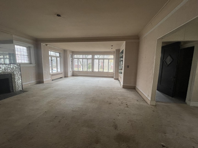 unfurnished living room featuring ornamental molding, light carpet, and a tiled fireplace