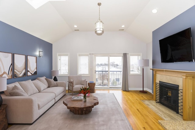 living room with plenty of natural light, light hardwood / wood-style floors, and vaulted ceiling