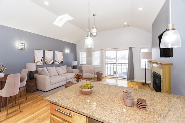 kitchen featuring light stone counters, lofted ceiling with skylight, and a wealth of natural light