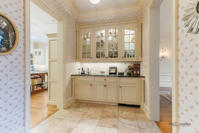 bar with sink, ornamental molding, light hardwood / wood-style floors, and cream cabinets