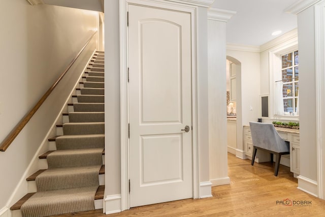 stairway featuring ornamental molding and hardwood / wood-style flooring