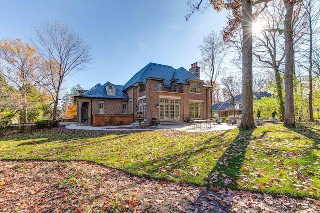 back of house featuring a lawn, french doors, and a patio