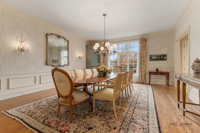 dining space featuring an inviting chandelier, ornamental molding, and light hardwood / wood-style floors