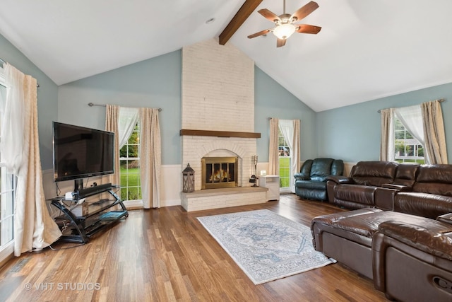 living room featuring a brick fireplace, ceiling fan, wood-type flooring, high vaulted ceiling, and beamed ceiling