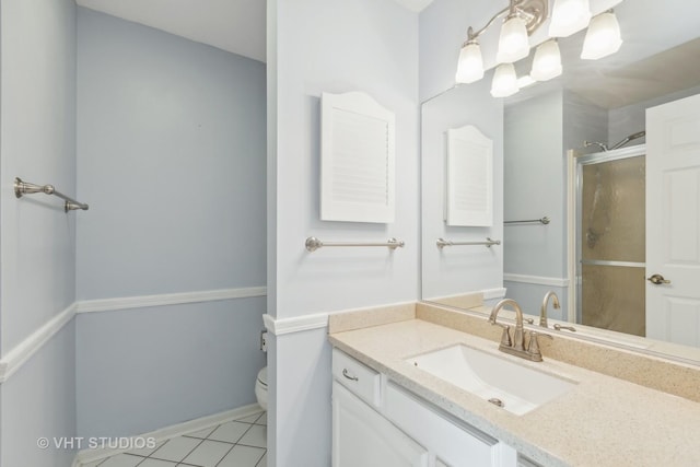 bathroom with tile patterned flooring, vanity, toilet, and a shower with shower door