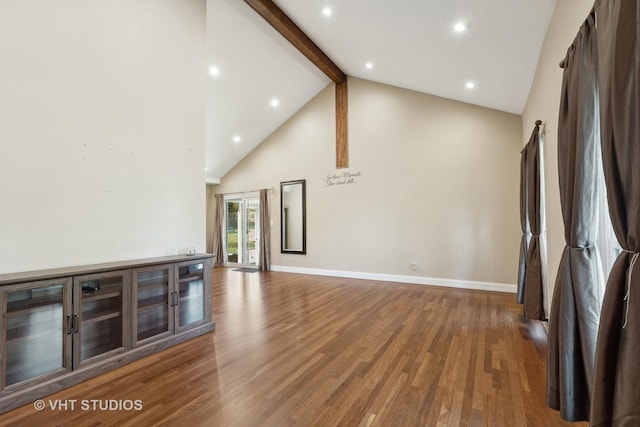 unfurnished living room featuring beamed ceiling, wood-type flooring, and high vaulted ceiling