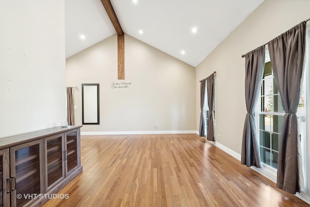 unfurnished living room with beam ceiling, light wood-type flooring, and high vaulted ceiling