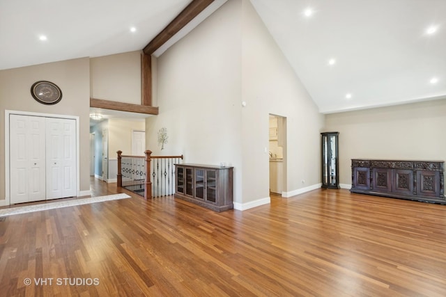 unfurnished living room with high vaulted ceiling and light wood-type flooring