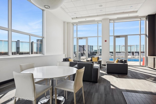 dining space featuring a drop ceiling, a tray ceiling, a wall of windows, and wood finished floors