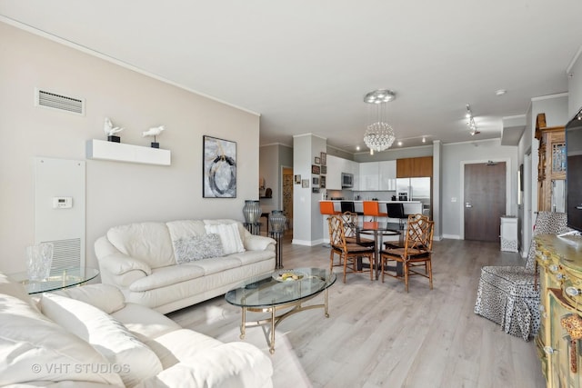 living area with baseboards, visible vents, crown molding, and light wood finished floors