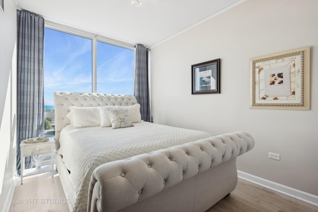 bedroom featuring crown molding, baseboards, and wood finished floors