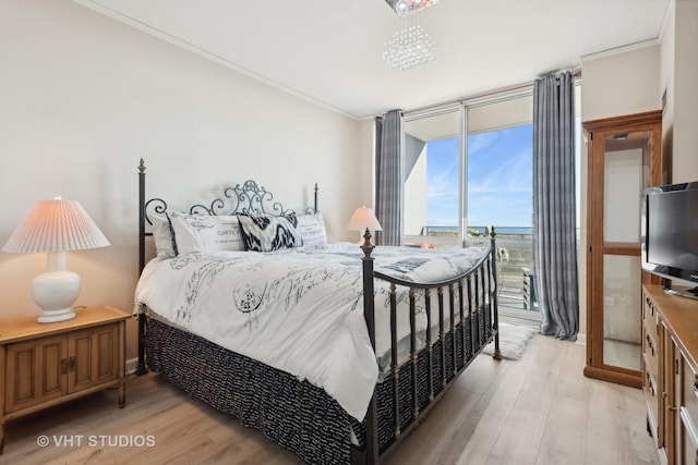 bedroom with ornamental molding, light wood-style flooring, and floor to ceiling windows