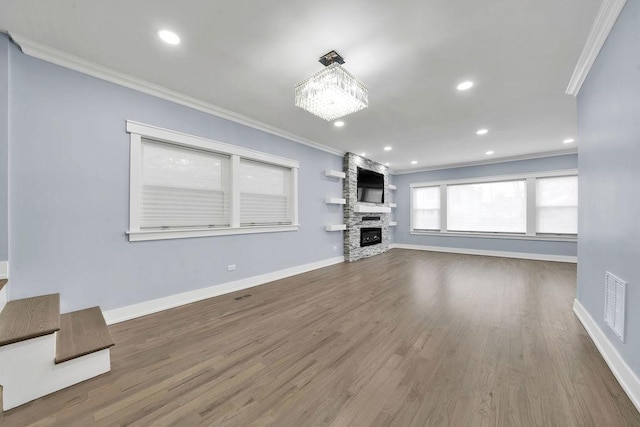 unfurnished living room featuring a notable chandelier, crown molding, wood-type flooring, and a fireplace