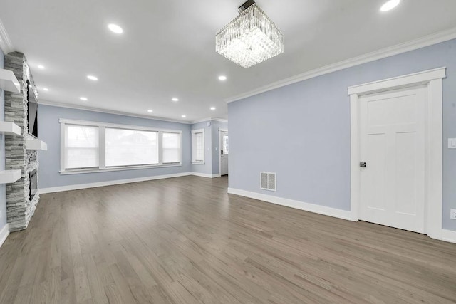 unfurnished living room with ornamental molding, a fireplace, a chandelier, and hardwood / wood-style flooring