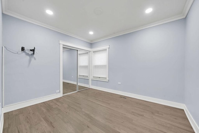 unfurnished bedroom with crown molding, a closet, and hardwood / wood-style floors