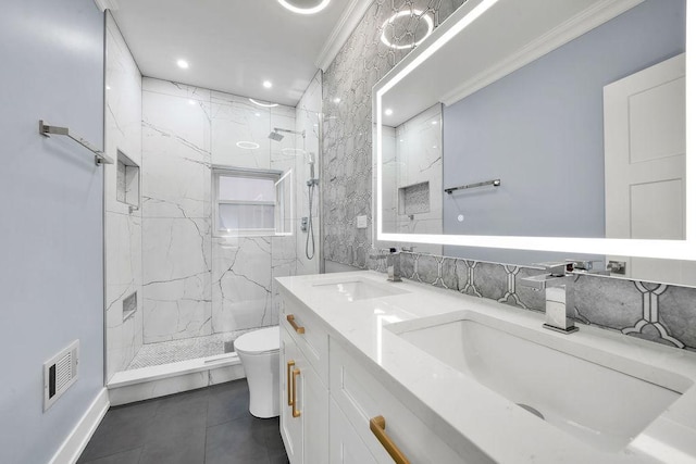 bathroom with ornamental molding, vanity, tiled shower, tile patterned flooring, and toilet