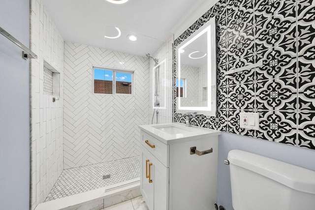 bathroom with vanity, toilet, tiled shower, and crown molding