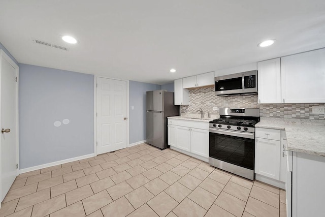 kitchen with white cabinets, stainless steel appliances, light stone countertops, and sink