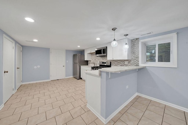 kitchen featuring tasteful backsplash, kitchen peninsula, pendant lighting, white cabinets, and appliances with stainless steel finishes