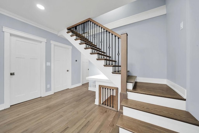 stairs with hardwood / wood-style floors and ornamental molding