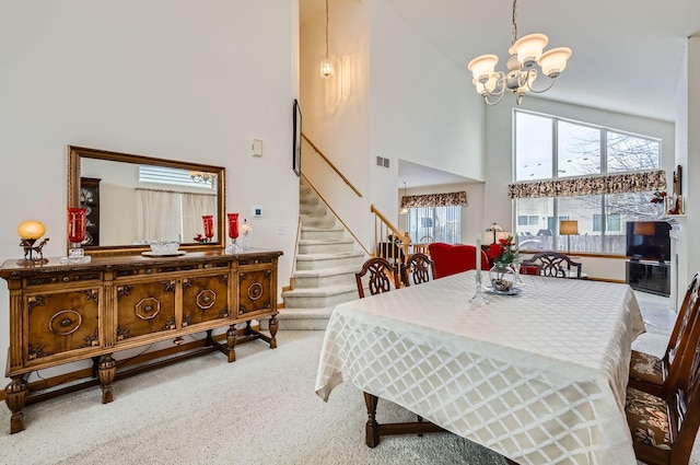 dining space featuring an inviting chandelier, light colored carpet, and high vaulted ceiling